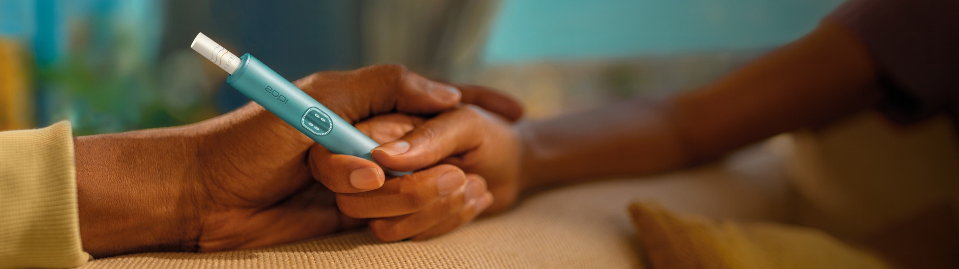 امرأة تحمل جهاز IQOS وهي تنظر إلى جهاز كمبيوتر محمول.